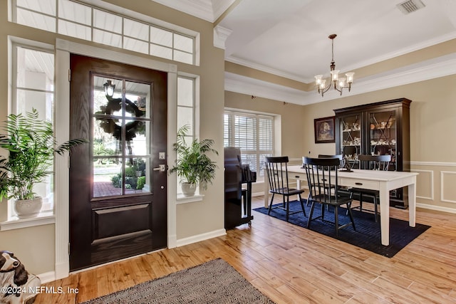 foyer featuring a chandelier, crown molding, light hardwood / wood-style flooring, and a healthy amount of sunlight