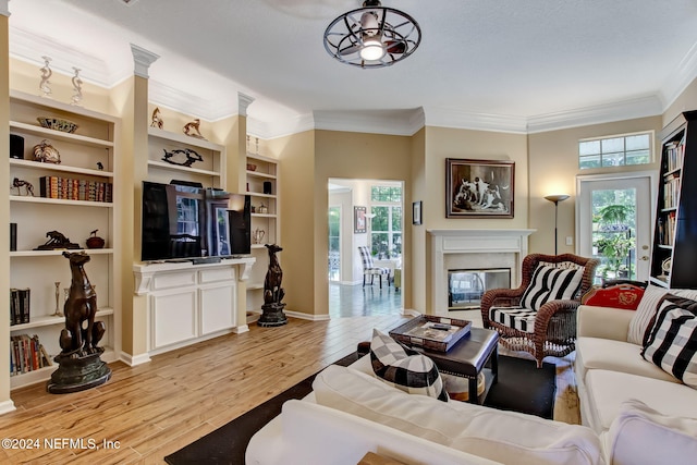 living room featuring ceiling fan, ornamental molding, a healthy amount of sunlight, and light wood-type flooring