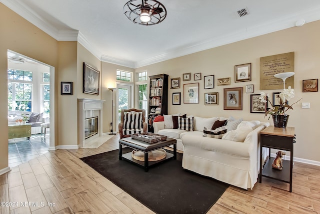 living room featuring a premium fireplace, crown molding, ceiling fan, and light wood-type flooring