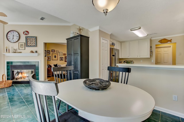 tiled dining room with crown molding and a tiled fireplace