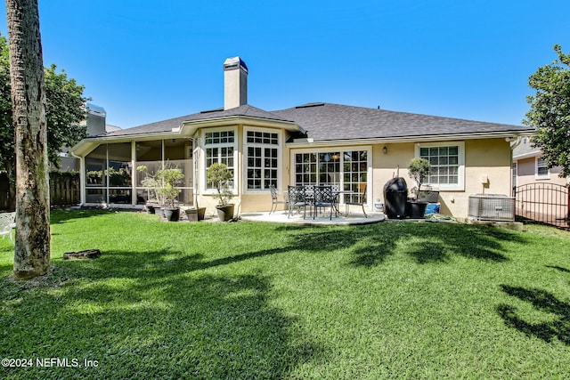 rear view of property with a lawn, a sunroom, cooling unit, and a patio area