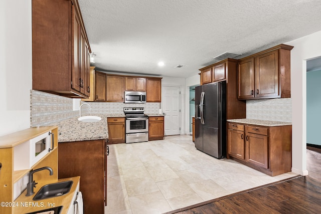 kitchen with tasteful backsplash, sink, stainless steel appliances, and light wood-type flooring