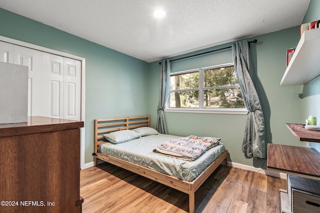 bedroom featuring light wood-type flooring, a textured ceiling, and a closet