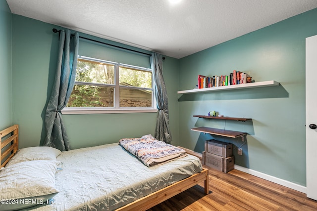 bedroom featuring a textured ceiling and hardwood / wood-style flooring