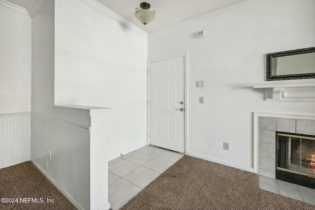 entrance foyer featuring a tile fireplace, light carpet, a textured ceiling, and ornamental molding