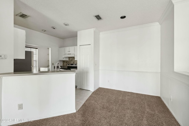 kitchen featuring white cabinets, kitchen peninsula, and light carpet