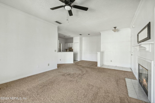 unfurnished living room with light carpet, ceiling fan, ornamental molding, a textured ceiling, and a fireplace