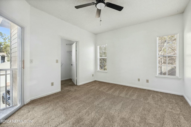 unfurnished bedroom with ceiling fan, a spacious closet, a textured ceiling, carpet floors, and a closet