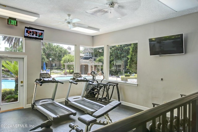 gym featuring ceiling fan, a healthy amount of sunlight, and a textured ceiling