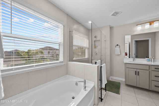 bathroom featuring tile patterned floors, vanity, plus walk in shower, and a textured ceiling