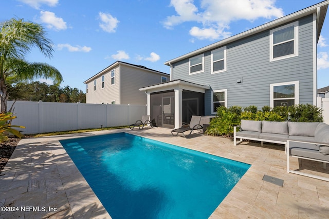 view of pool with a sunroom, an outdoor living space, and a patio