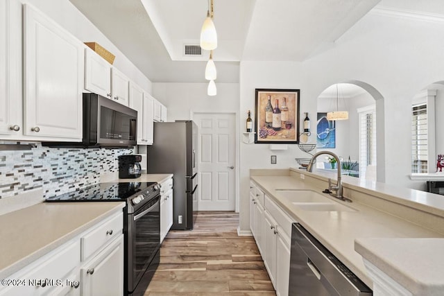 kitchen featuring sink, hanging light fixtures, stainless steel appliances, light hardwood / wood-style flooring, and white cabinets