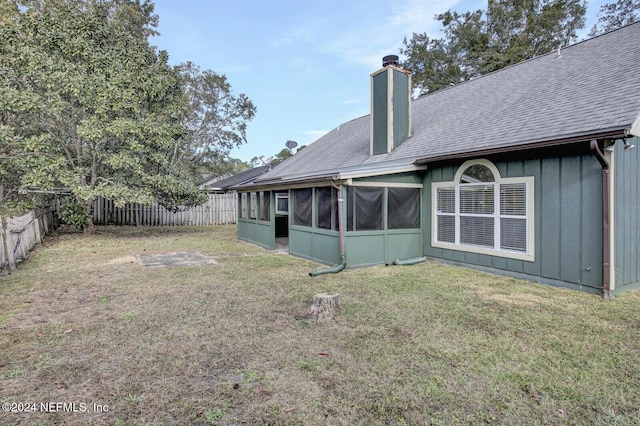 back of property with a lawn and a sunroom