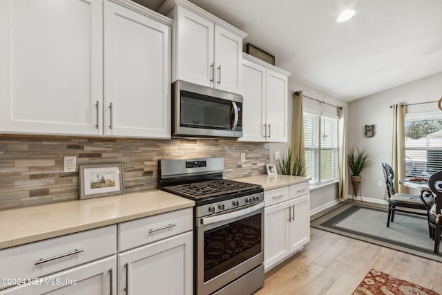 kitchen featuring light wood-type flooring, stainless steel appliances, white cabinetry, and a healthy amount of sunlight