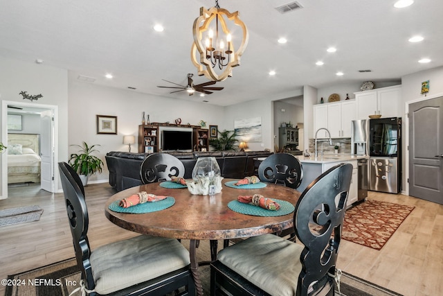 dining room with ceiling fan with notable chandelier and light hardwood / wood-style floors