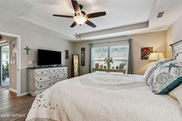 bedroom featuring a raised ceiling, ceiling fan, hardwood / wood-style floors, and access to outside