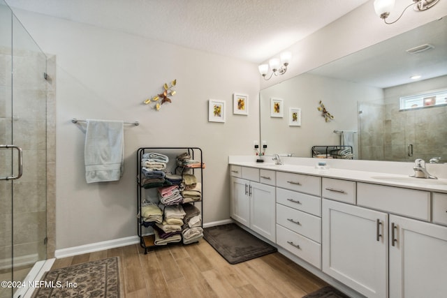 bathroom featuring vanity, a shower with door, wood-type flooring, and a textured ceiling