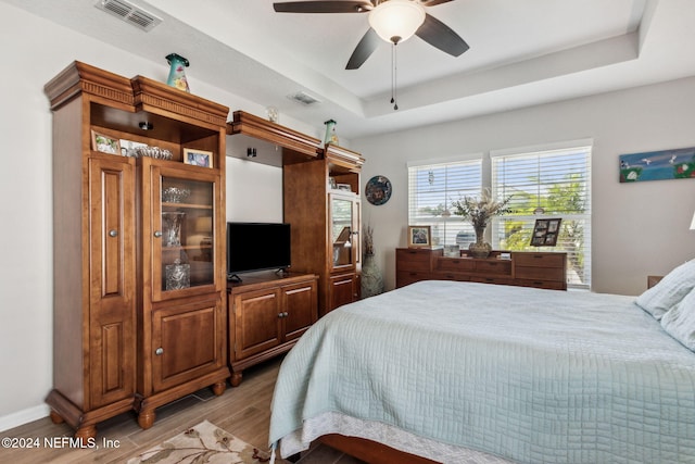 bedroom featuring a tray ceiling, ceiling fan, and hardwood / wood-style flooring