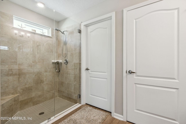 bathroom featuring hardwood / wood-style floors, a shower with shower door, and a textured ceiling