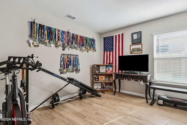 exercise room featuring a textured ceiling and hardwood / wood-style flooring