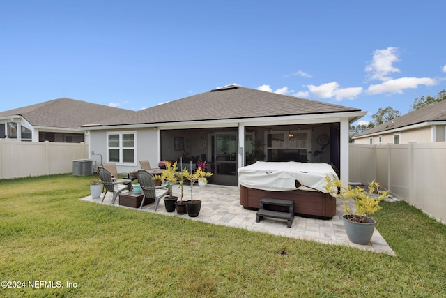 rear view of property with central air condition unit, a patio area, a yard, and a hot tub