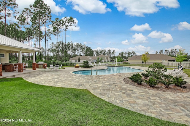 view of pool featuring a grill, a patio area, an outdoor bar, and a yard