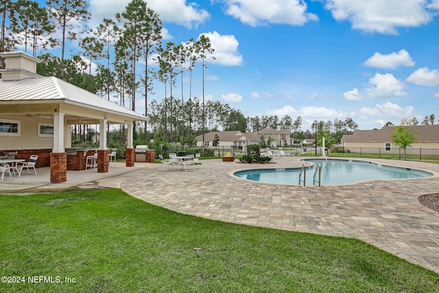 view of swimming pool featuring exterior bar, a patio, exterior kitchen, and a lawn