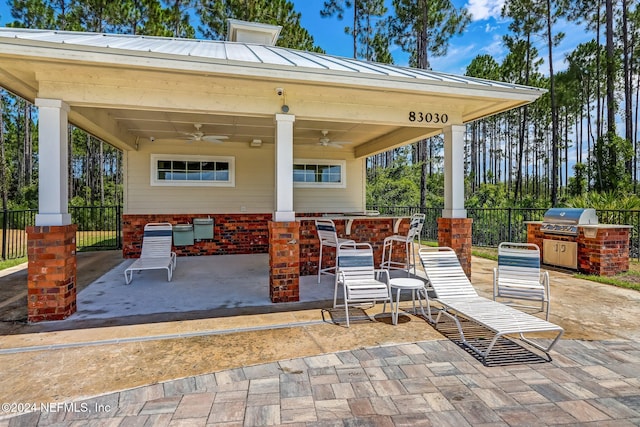 view of patio with exterior bar, grilling area, ceiling fan, and exterior kitchen