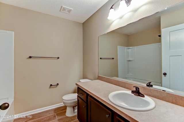 full bathroom featuring shower / bathing tub combination, vanity, hardwood / wood-style flooring, toilet, and a textured ceiling