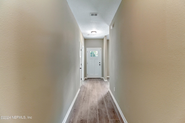 corridor with hardwood / wood-style floors and a textured ceiling