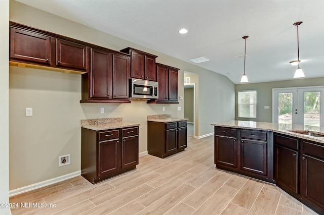 kitchen with decorative light fixtures, light stone countertops, and light wood-type flooring