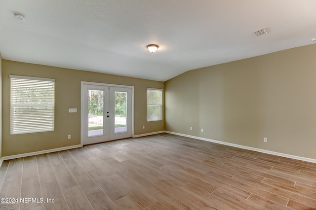 unfurnished room with french doors, lofted ceiling, and light wood-type flooring