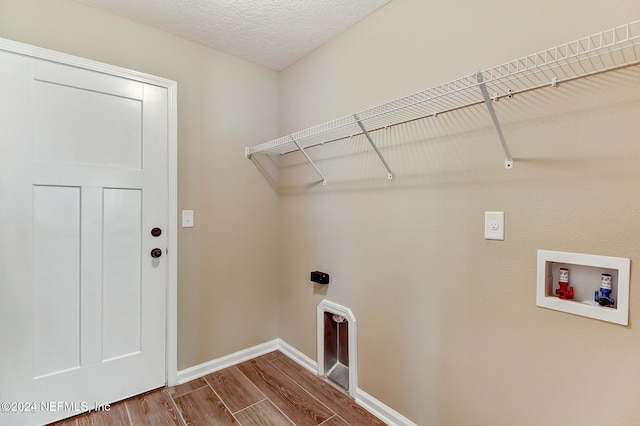 laundry area with electric dryer hookup, hookup for a washing machine, a textured ceiling, and hardwood / wood-style flooring