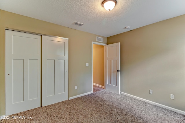 unfurnished bedroom featuring carpet, a textured ceiling, and a closet