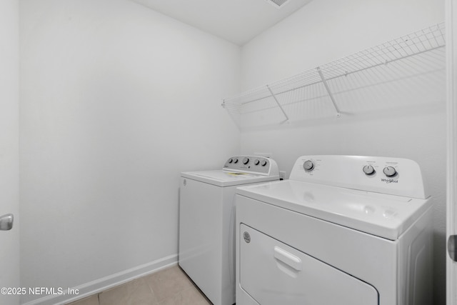 washroom with light tile patterned floors, visible vents, washer and dryer, laundry area, and baseboards