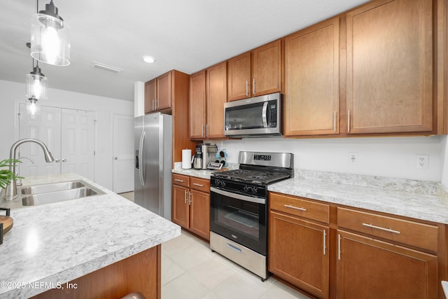 kitchen featuring brown cabinets, light countertops, hanging light fixtures, appliances with stainless steel finishes, and a sink