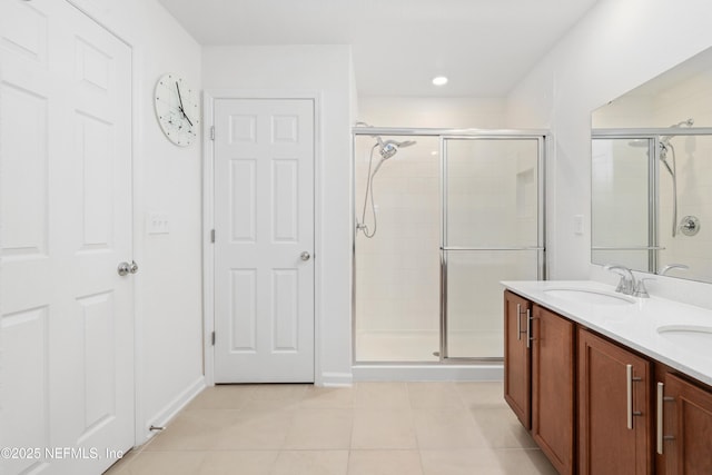 full bathroom with double vanity, a stall shower, a sink, and tile patterned floors