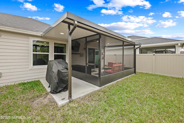 rear view of property with roof with shingles, a lawn, a patio, and fence