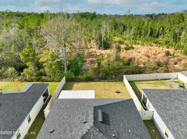 view of home's community featuring a fenced backyard, a lawn, and a view of trees