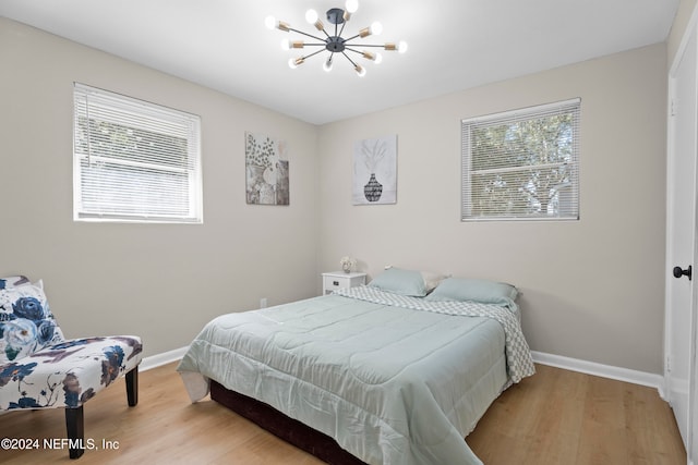 bedroom with wood-type flooring and an inviting chandelier