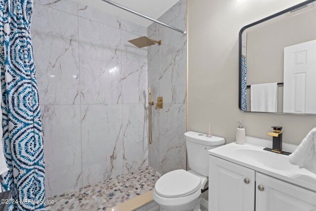 bathroom with a tile shower, vanity, and toilet