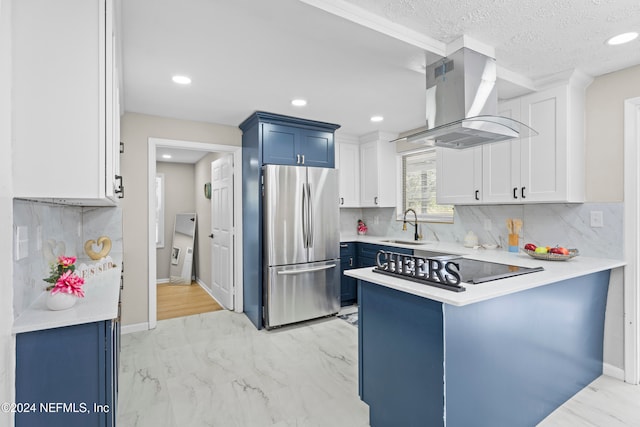 kitchen featuring blue cabinets, sink, stainless steel fridge, island range hood, and white cabinetry