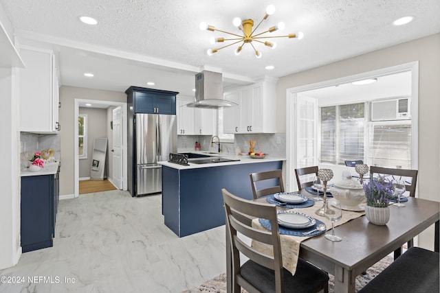 kitchen featuring blue cabinetry, stainless steel fridge, white cabinets, and exhaust hood