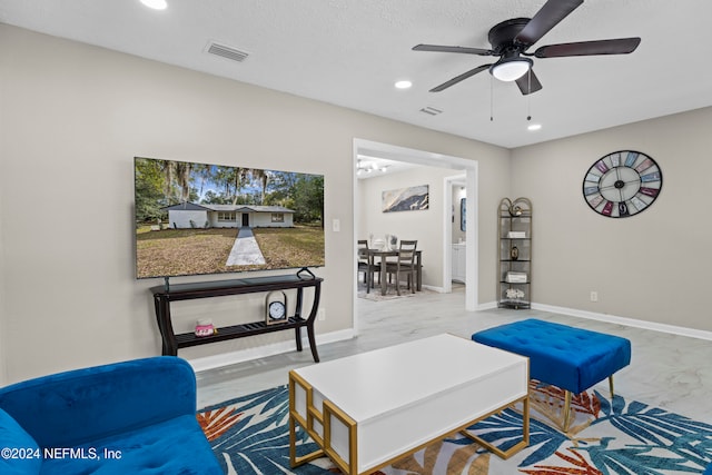 living room featuring ceiling fan and a textured ceiling