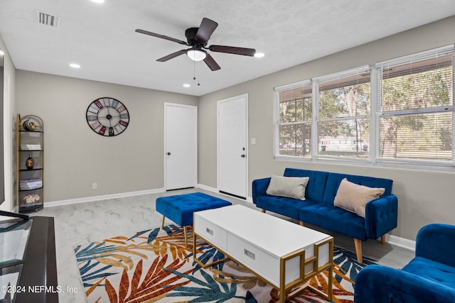 living room featuring ceiling fan and a textured ceiling