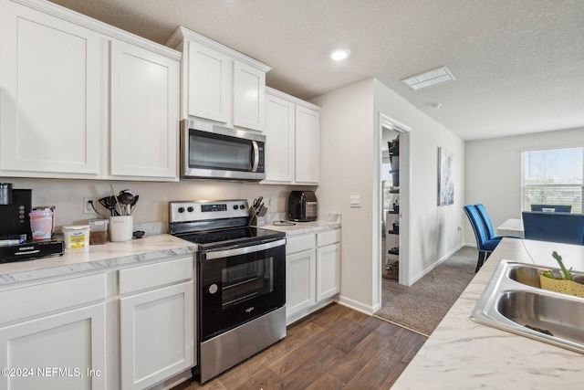 kitchen with stainless steel appliances, white cabinetry, dark wood-type flooring, and sink