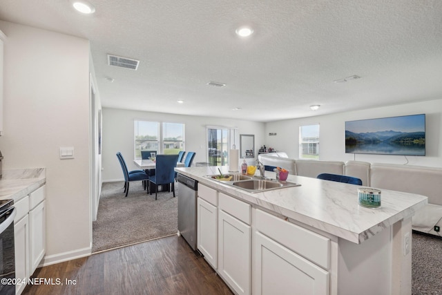 kitchen with stainless steel appliances, a kitchen island with sink, sink, white cabinets, and dark hardwood / wood-style floors