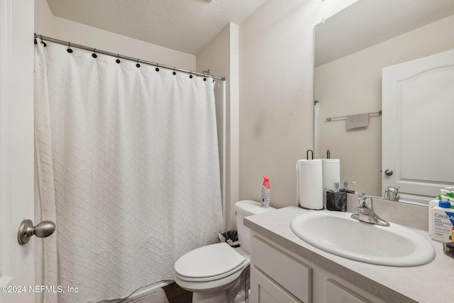 bathroom with vanity, toilet, and a textured ceiling