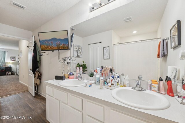 bathroom with hardwood / wood-style flooring, vanity, and a textured ceiling