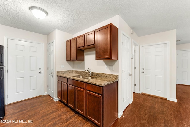 kitchen featuring a textured ceiling, light stone countertops, sink, and dark hardwood / wood-style floors